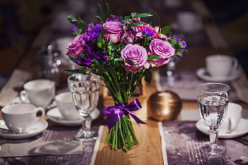 Flowers composition in restaurant,  roses and irises, combination shades of purple