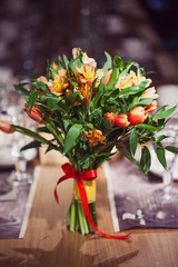 Flowers composition in restaurant, small red roses and purple irises, combination of multiple colors