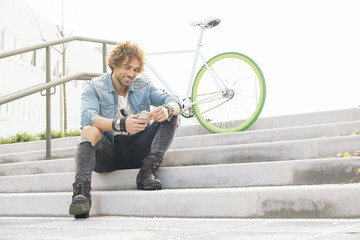 Handsome young man with mobile phone and fixed gear bicycle.