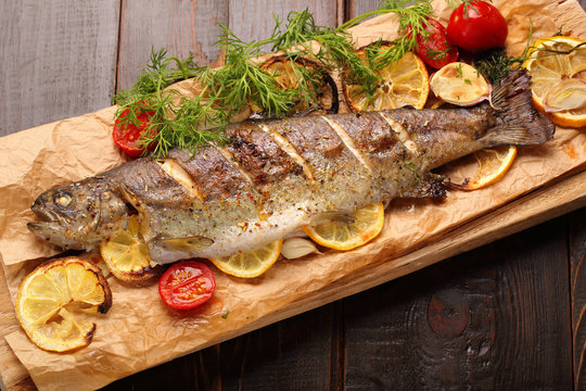 Baked fish with lemon on wooden background