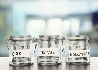 Three jars for different needs full of banknotes on bright background
