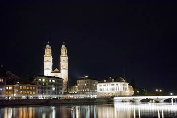 Night photo of Grossmunster church and bridge over Limmat River, city of Zurich, Switzerland