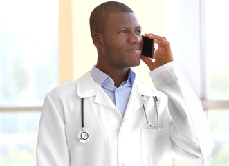 Handsome African American doctor talking on mobile phone in hospital