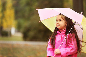 Beautiful little girl with umbrella in park
