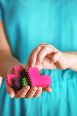 Closeup of plastic puzzle hearts in female hands