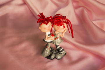 souvenir statuette of a boy and a girl on a pink silk