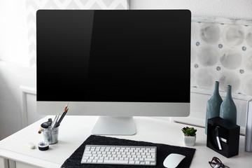 Modern wide screen monitor on white table in room interior