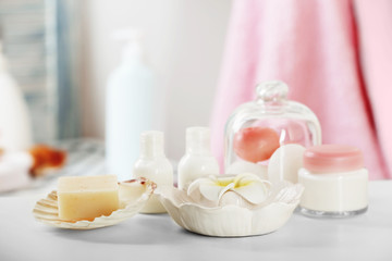 Fototapeta na wymiar Soap with cosmetic and tropical flower on bathroom table