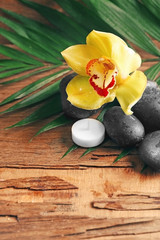 Spa stones with beautiful flowers and candles on wooden background