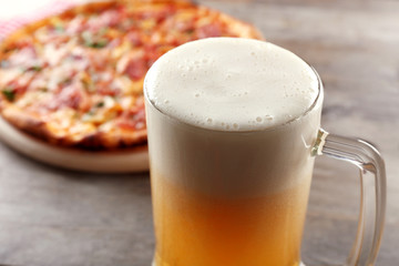 Tasty pizza and glass of beer are on wooden table, close up