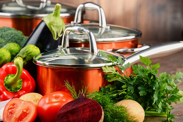 Composition with set of pots and raw vegetables