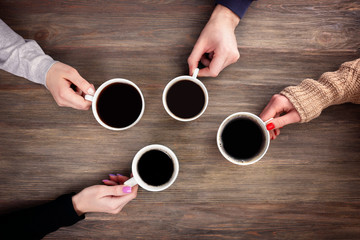 Friends drinking coffee on wooden table