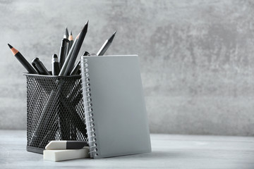 Pens and pencils in metal holder in front of wall background - Powered by Adobe