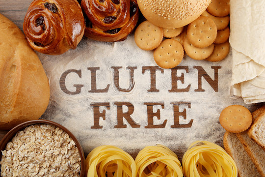 Text GLUTEN FREE with bakery products and flour on wooden surface closeup