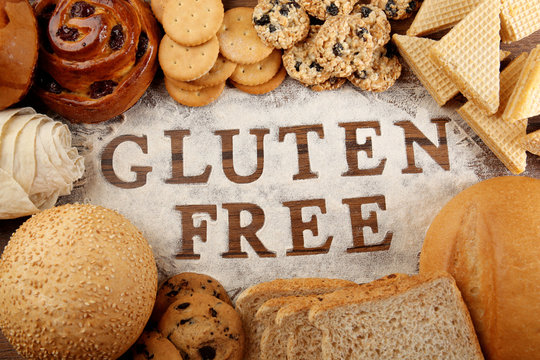 Text GLUTEN FREE with bakery products and flour on wooden surface closeup