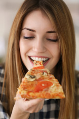 Happy young woman eating slice of hot pizza, close up