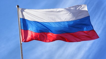 Flag of Russia. Russian Flag on Flagpole Waving in front of Blue Sky.