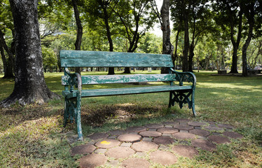An old green wooden chair in a park
