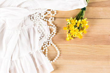 Beautiful white cloth, pearl beads and yellow daffodil on  the table.