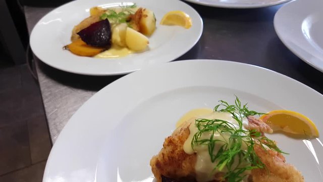 Battered perch filet dishes, with, dill, golden beetroot, potatoes and hollandaise sauce, at a restaurant kitchen