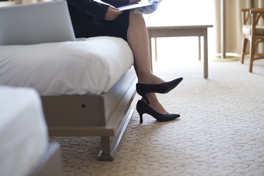 Feet of business woman sitting on a bed in a hotel room