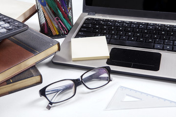 Glasses with laptop and books on table
