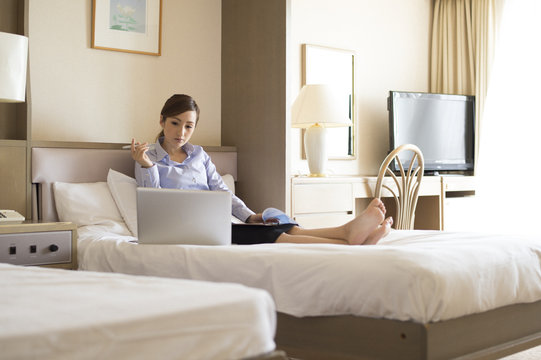 Women have to work with a laptop sitting on the business hotel bed