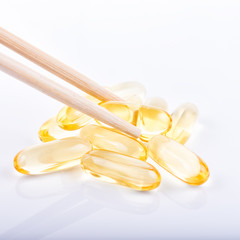 Cod liver oil omega 3 gel capsules in bowl on floor wood