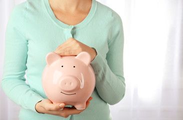 Obraz na płótnie Canvas Woman holding piggy bank in hand. Financial savings concept