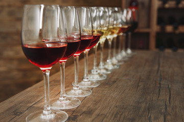 Many glasses of different wine in a row on bar counter