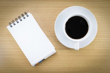 Obraz na płótnie Canvas Coffee and notepad on wood table