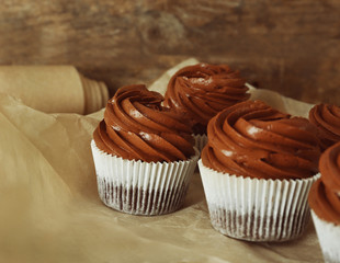Chocolate cupcakes on baker paper over wooden background