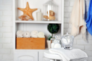 Fototapeta na wymiar Bathroom set with towels and sponges on stool in light interior