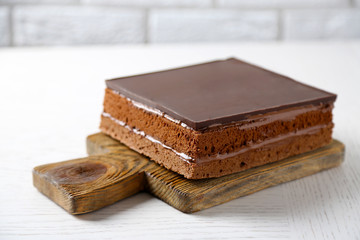 Delicious chocolate cake on wooden cutting board closeup