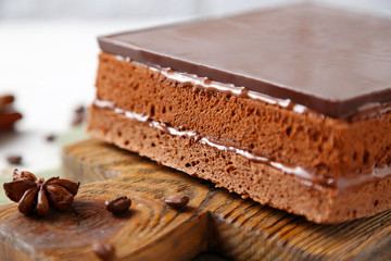 Delicious chocolate cake on wooden cutting board closeup