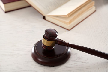 Gavel with books on wooden table closeup