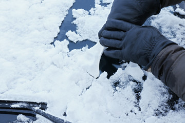 Removing snow from car windshield, closeup