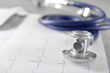 Cardiogram chart with medical stethoscope on table closeup