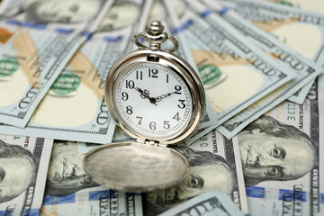 Time is money concept with pocket watch and dollars bills closeup