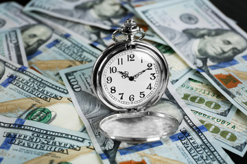 Time is money concept with pocket watch and dollars bills closeup