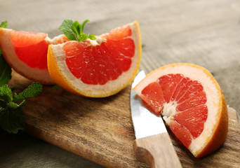 Sliced grapefruits with mint on wooden background, close up