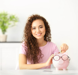 Beautiful young girl with piggy bank in office