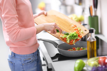 Woman frying vegetables in kitchen