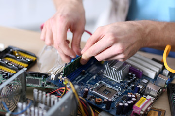 Young man repairing computer hardware in service center
