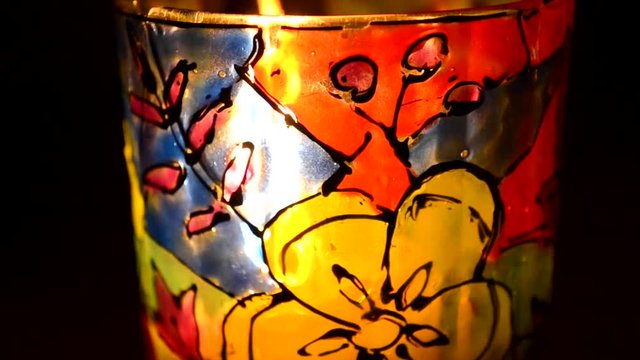 candle flame shines in a colorful candlestick