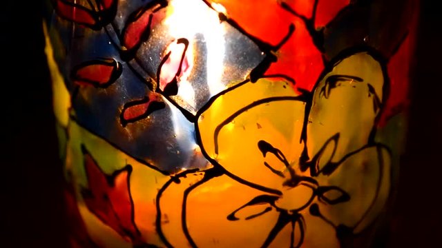 candle flame shines in a colorful candlestick