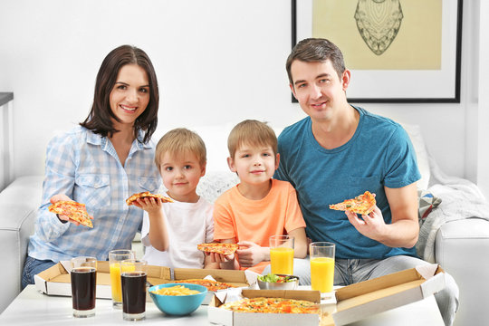 Happy family eating pizza on sofa all together
