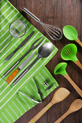 Set of kitchen tools with green napkin on wooden table