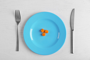 Slices of baby carrots in a blue plate on white table. Top view.