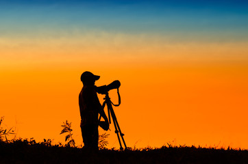 silhouette of photographer taking picture of landscape during su